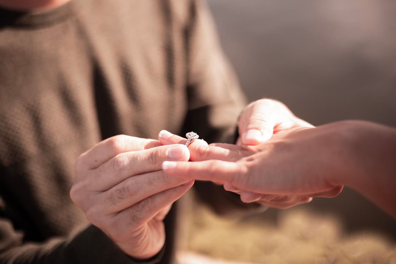 man putting diamond ring on woman's hand 