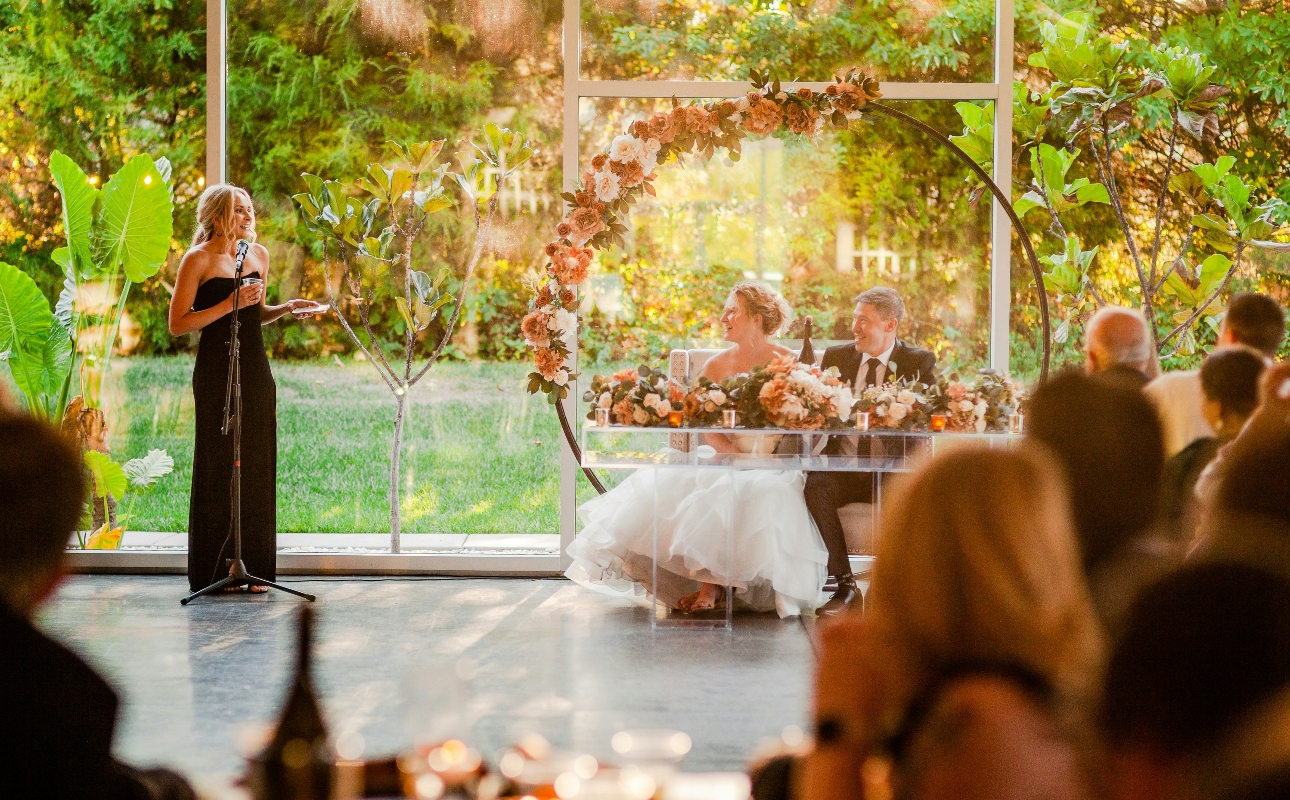 bridesmaid in black dress given a speech on a mike at a wedding