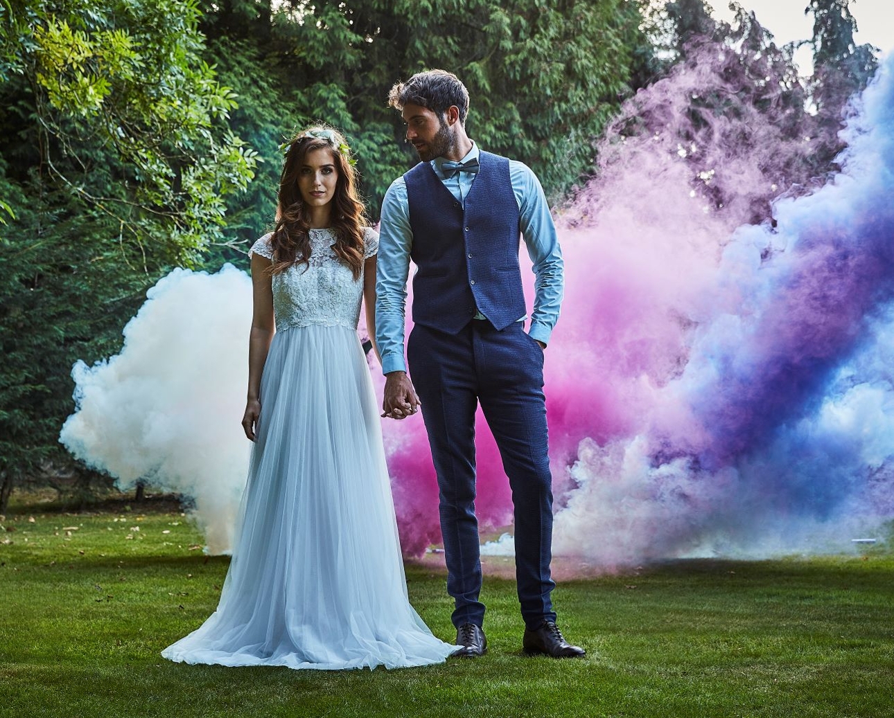 bride and groom holding hands in front of smoke bomb